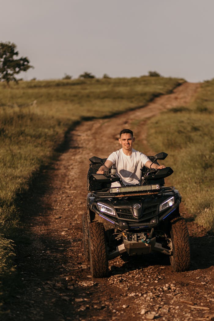 services-02 A man enjoying a ride on a quad bike along a scenic countryside trail on a sunny day.