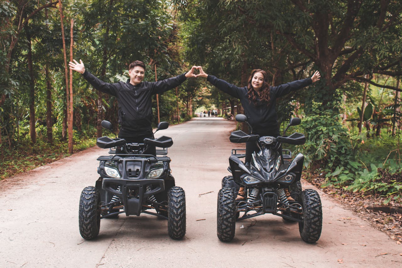 gallery-1 A joyful couple riding quad bikes on a forest road, expressing love and adventure.