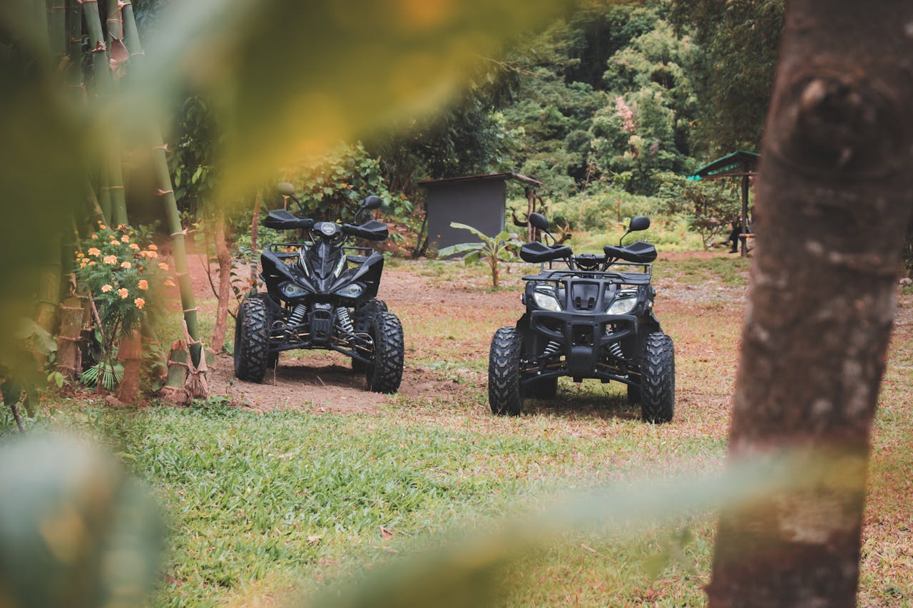 why-choose-us Two all-terrain vehicles parked in a serene forest setting. Ideal for adventure seekers.